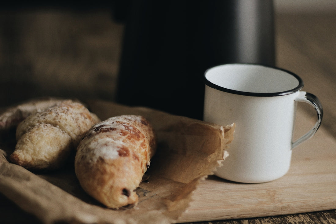 two breads on paper bag beside cup
