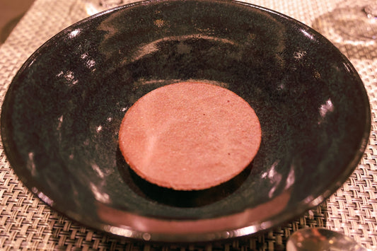 A black plate on a table with silverware