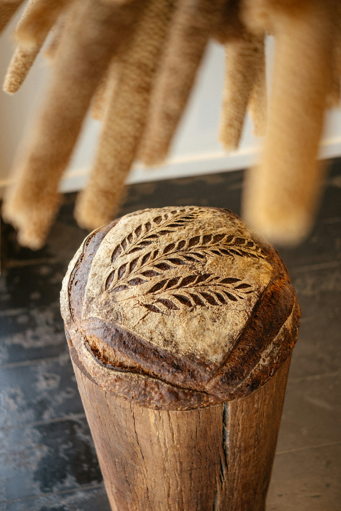Beautifully carved sourdough bread sits on a wooden stand.