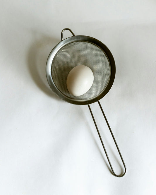 An egg in a frying pan on a white sheet