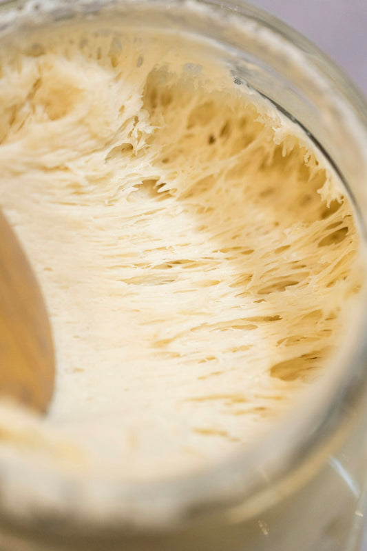 A wooden spoon inside of a jar filled with liquid